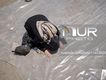 An Iraqi woman living in Iran is praying during a religious festival to commemorate Ashura in the Dolatabad neighborhood in southern Tehran,...