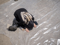 An Iraqi woman living in Iran is praying during a religious festival to commemorate Ashura in the Dolatabad neighborhood in southern Tehran,...