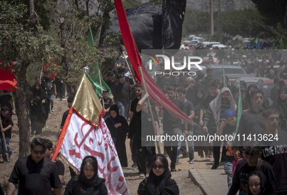 A young Iraqi boy living in Iran is carrying a giant religious flag while participating in a religious festival to commemorate Ashura in the...