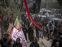 A young Iraqi boy living in Iran is carrying a giant religious flag while participating in a religious festival to commemorate Ashura in the...