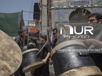 Iraqi men living in Iran are carrying traditional musical instruments while participating in a religious festival to commemorate Ashura in t...