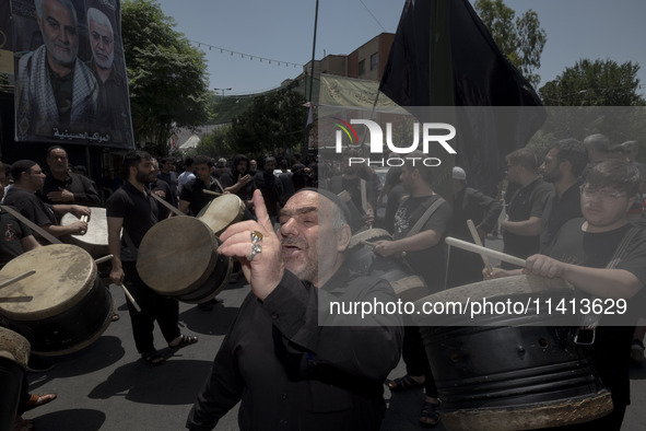 An elderly Iraqi man living in Iran is singing a religious song while the other men are playing traditional musical instruments during a rel...