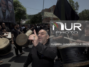 An elderly Iraqi man living in Iran is singing a religious song while the other men are playing traditional musical instruments during a rel...