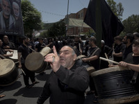 An elderly Iraqi man living in Iran is singing a religious song while the other men are playing traditional musical instruments during a rel...