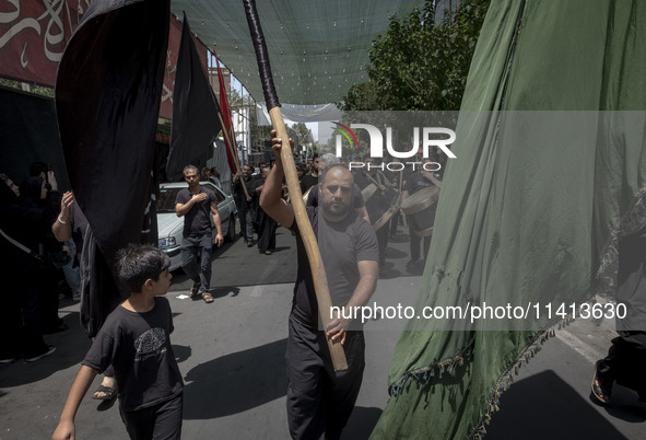 An Iraqi man living in Iran is carrying a giant religious flag while participating in a religious festival to commemorate Ashura, in the Dol...