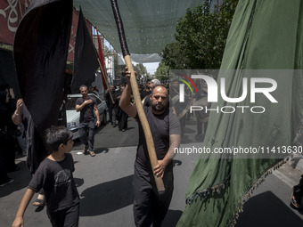 An Iraqi man living in Iran is carrying a giant religious flag while participating in a religious festival to commemorate Ashura, in the Dol...