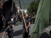 An Iraqi man living in Iran is carrying a giant religious flag while participating in a religious festival to commemorate Ashura, in the Dol...