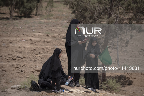 A veiled Iraqi woman and her veiled daughters are standing in an area after participating in a religious festival to commemorate Ashura, in...