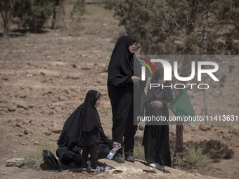 A veiled Iraqi woman and her veiled daughters are standing in an area after participating in a religious festival to commemorate Ashura, in...