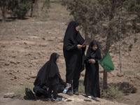 A veiled Iraqi woman and her veiled daughters are standing in an area after participating in a religious festival to commemorate Ashura, in...