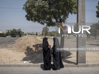 Two veiled Iraqi women are standing together on a street side after participating in a religious festival to commemorate Ashura, in Dolataba...