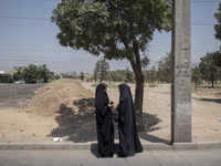 Two veiled Iraqi women are standing together on a street side after participating in a religious festival to commemorate Ashura, in Dolataba...