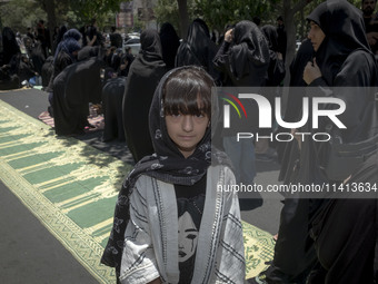 A young girl is posing for a photograph while veiled women are preparing to take part in a mass prayer ceremony during a religious festival...