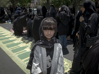 A young girl is posing for a photograph while veiled women are preparing to take part in a mass prayer ceremony during a religious festival...