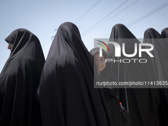 A young veiled girl is looking on while standing next to her mother during a religious festival to commemorate Ashura, in Dolatabad neighbor...