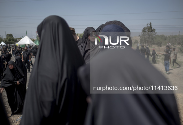 A veiled woman is looking on while participating in a religious festival to commemorate Ashura, in Dolatabad neighborhood in southern Tehran...