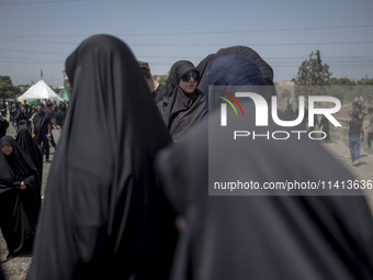 A veiled woman is looking on while participating in a religious festival to commemorate Ashura, in Dolatabad neighborhood in southern Tehran...