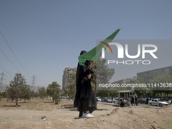 A young veiled Iraqi girl living in Iran is holding a religious flag during a religious festival to commemorate Ashura in the Dolatabad neig...