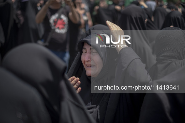 A veiled woman is beating herself while participating in a religious festival to commemorate Ashura, in Dolatabad neighborhood in southern T...