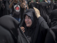 A veiled woman is beating herself while participating in a religious festival to commemorate Ashura, in Dolatabad neighborhood in southern T...