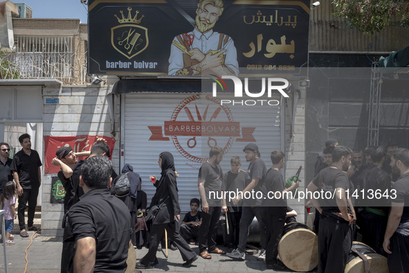 Young Iraqi men are standing together on a sidewalk during a religious festival to commemorate Ashura, in the Dolatabad neighborhood in sout...