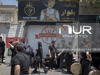 Young Iraqi men are standing together on a sidewalk during a religious festival to commemorate Ashura, in the Dolatabad neighborhood in sout...