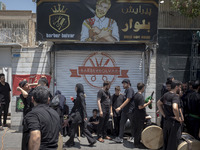 Young Iraqi men are standing together on a sidewalk during a religious festival to commemorate Ashura, in the Dolatabad neighborhood in sout...