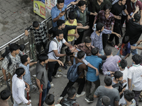 An injured anti-quota protestor is being taken to a hospital during a clash with the pro-government student wing in Dhaka, Bangladesh, on Ju...