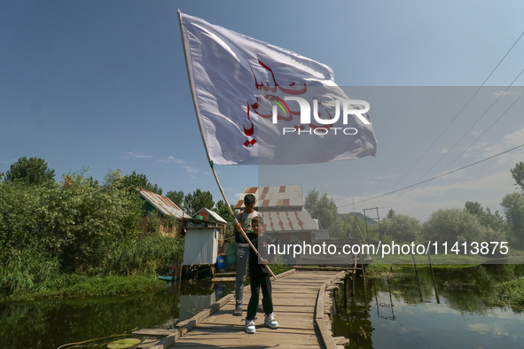 A Kashmiri Shia Muslim boy is waving a flag during a procession in the interiors of Dal Lake in Srinagar, Indian Administered Kashmir, on Ju...