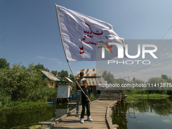 A Kashmiri Shia Muslim boy is waving a flag during a procession in the interiors of Dal Lake in Srinagar, Indian Administered Kashmir, on Ju...