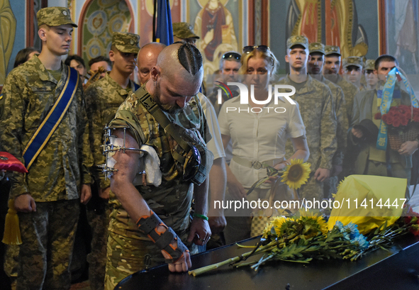 A serviceman is paying his last respects to the commander of the OUN volunteer battalion, Mykola Kokhanivskyi, who died near Vovchansk in th...