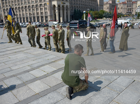 A kneeling man is meeting the procession with the coffin of the commander of the OUN volunteer battalion Mykola Kokhanivskyi, who died near...