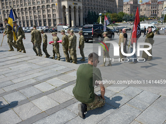 A kneeling man is meeting the procession with the coffin of the commander of the OUN volunteer battalion Mykola Kokhanivskyi, who died near...