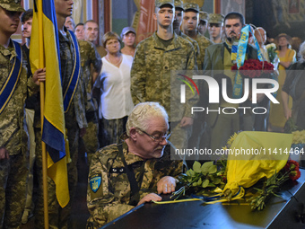 A serviceman is paying his last respects to the commander of the OUN volunteer battalion, Mykola Kokhanivskyi, who died near Vovchansk in th...