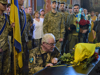 A serviceman is paying his last respects to the commander of the OUN volunteer battalion, Mykola Kokhanivskyi, who died near Vovchansk in th...