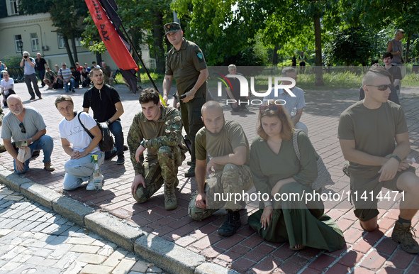 People are kneeling outside the St Michael's Golden-Domed Monastery as they are welcoming the funeral procession of the commander of the OUN...