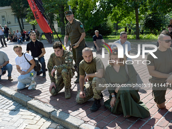 People are kneeling outside the St Michael's Golden-Domed Monastery as they are welcoming the funeral procession of the commander of the OUN...