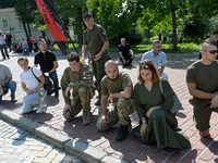 People are kneeling outside the St Michael's Golden-Domed Monastery as they are welcoming the funeral procession of the commander of the OUN...