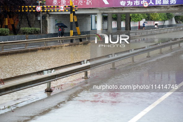 People are wading through water at the Nanyuan overpass in Shizhong District of Zaozhuang city, East China's Shandong province, on July 17,...