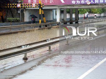 People are wading through water at the Nanyuan overpass in Shizhong District of Zaozhuang city, East China's Shandong province, on July 17,...