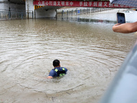 Law enforcement officers of Shizhong District Comprehensive Administrative Law Enforcement Bureau are wading through a waterlogged road in Z...