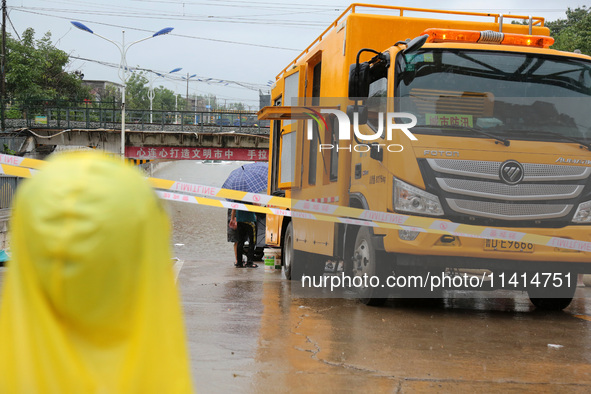 Citizens are stopping to watch law enforcement officers pump out water with a large-flow drainage vehicle at a waterlogged road section in S...