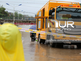 Citizens are stopping to watch law enforcement officers pump out water with a large-flow drainage vehicle at a waterlogged road section in S...