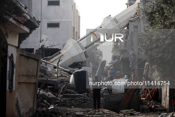 Palestinians are standing on the rubble of Abdullah Azzam Mosque, destroyed in Israeli bombardment in Nuseirat, central Gaza Strip, on July...