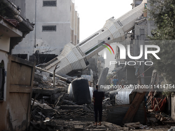 Palestinians are standing on the rubble of Abdullah Azzam Mosque, destroyed in Israeli bombardment in Nuseirat, central Gaza Strip, on July...