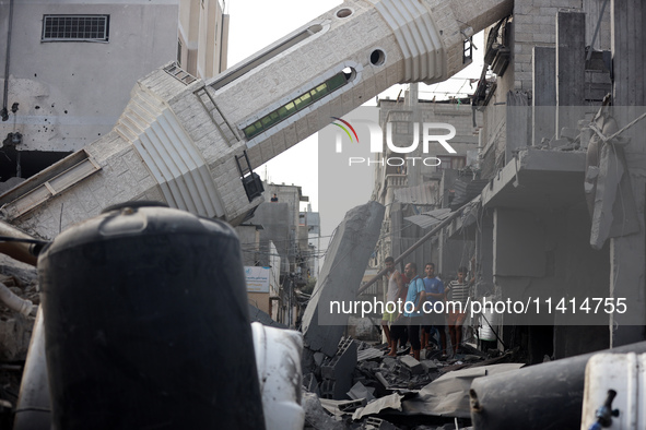 Palestinians are standing on the rubble of Abdullah Azzam Mosque, destroyed in Israeli bombardment in Nuseirat, central Gaza Strip, on July...