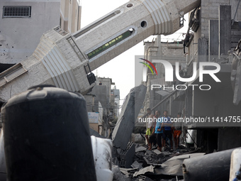 Palestinians are standing on the rubble of Abdullah Azzam Mosque, destroyed in Israeli bombardment in Nuseirat, central Gaza Strip, on July...