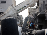 Palestinians are standing on the rubble of Abdullah Azzam Mosque, destroyed in Israeli bombardment in Nuseirat, central Gaza Strip, on July...