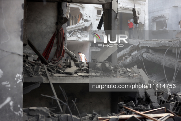 Palestinians are standing on the rubble of Abdullah Azzam Mosque, destroyed in Israeli bombardment in Nuseirat, central Gaza Strip, on July...