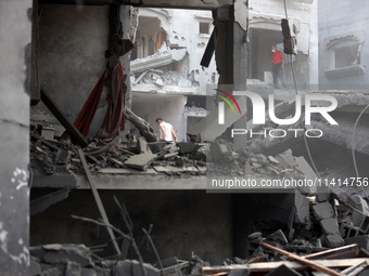 Palestinians are standing on the rubble of Abdullah Azzam Mosque, destroyed in Israeli bombardment in Nuseirat, central Gaza Strip, on July...